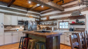 Cucina con travi in legno, mobili bianchi, isola centrale, sgabelli e un'atmosfera rustica.