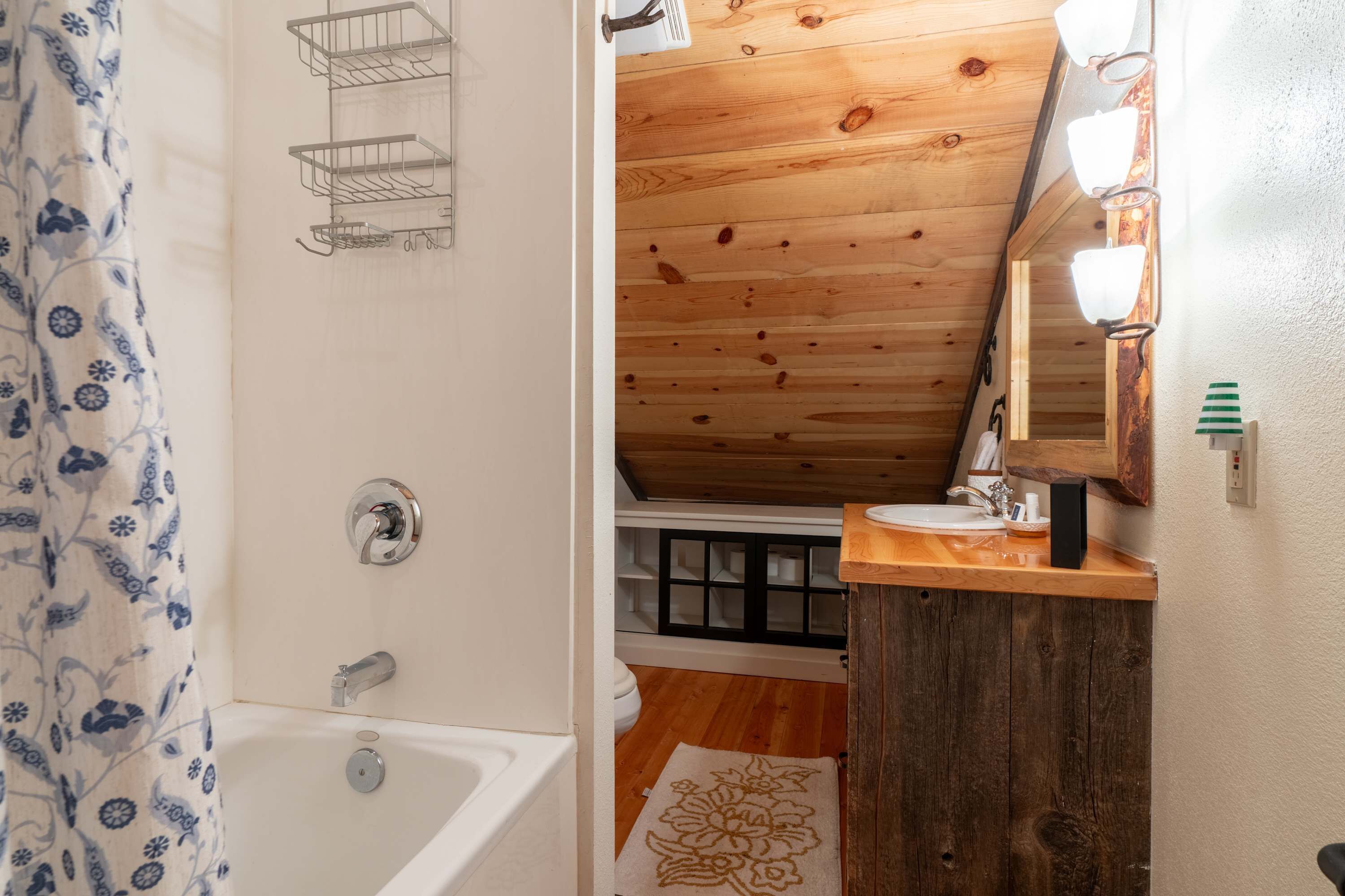 A bathroom with a wooden ceiling, a bathtub, a sink, and a mirror.