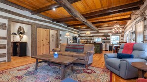 Un'ampia zona giorno con soffitto in legno, un divano, una poltrona reclinabile, un tavolino da caffè e un tappeto decorato.