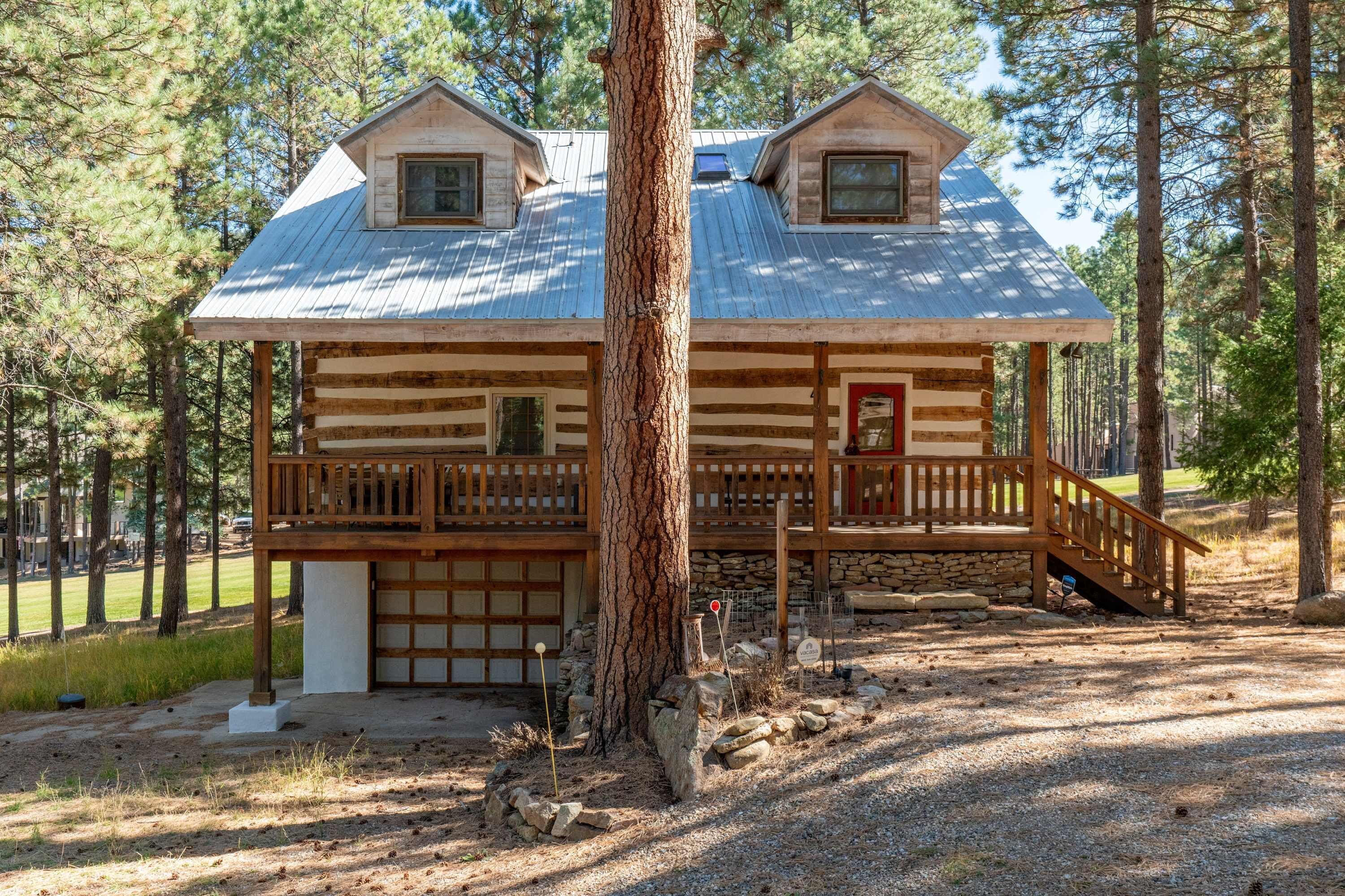 A log cabin with a porch, two windows, and a garage.
