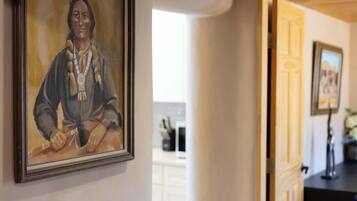 A framed portrait on a wall, a doorway leading to another room, and a glimpse of a kitchen area in the background.