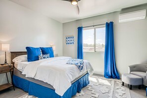 A bedroom with a bed, a nightstand, a lamp, a chair, a window with curtains, and an air conditioning unit. - Casa Ponderosa - Hot Tub, Bunk Room, Pet Friendly (Santa Fe)