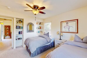 A bedroom with two beds, a ceiling fan, a bookshelf, a mirror, and a framed picture on the wall. - Closson Charmer - Courtyard & Steps to Railyard (Santa Fe)