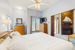 A bedroom with a bed, wooden dresser, television, and a fireplace. - Angel Fire Chalet 51 - Walk to Ski, Bike & Dining (Angel Fire)