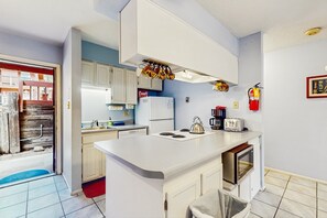 A compact kitchen with white cabinets, a built-in oven, a coffee maker, and a fire extinguisher. - Angel Fire Chalet 51 - Walk to Ski, Bike & Dining (Angel Fire)