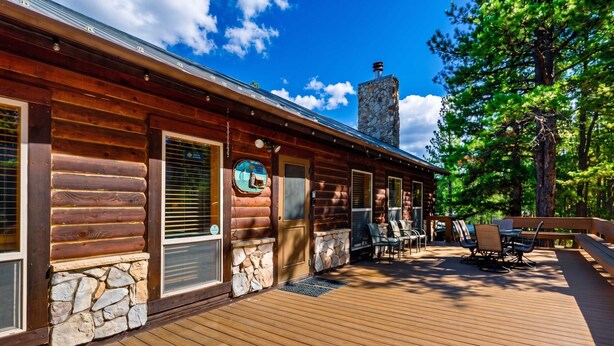 Eine Holzhütte mit einem Steinkamin, einer Holzdachterrasse und einer Sitzgelegenheit im Freien.