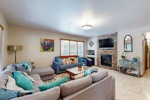 Ein Wohnzimmer mit einer Couch, einem Couchtisch, einem Kamin und einem Fernseher.