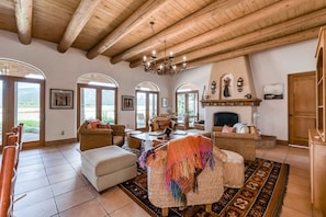 A spacious living room with a high wooden ceiling, a fireplace, and a dining area.