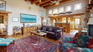 A spacious living area with a large rug, leather sofa, wooden furniture, and a ceiling fan. - Adobe Retreat - Walk to Plaza, Fireplace, Patio (Taos)