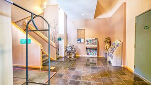 A hotel lobby with a staircase, a reception desk, a bulletin board, and a display of magazines. - Sweet Retreat - Ski Valley Condo, Gym, Game Room (Taos Ski Valley)