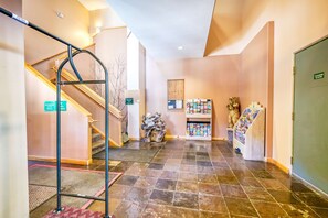 A hotel lobby with a staircase, a reception desk, a bulletin board, and a display of magazines.