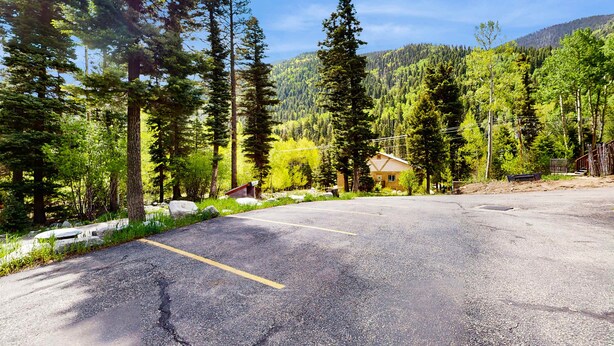 A parking lot with a building in the background surrounded by trees. - Sweet Retreat - Ski Valley Condo, Gym, Game Room (Taos Ski Valley)