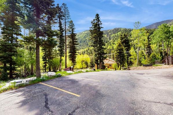 A parking lot with a building in the background surrounded by trees.