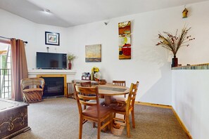 Un comedor con una mesa redonda, sillas de madera, un televisor de pantalla plana y una chimenea.