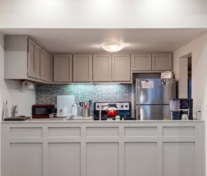 A kitchen with a stainless steel refrigerator, a microwave, a stove, and a sink.