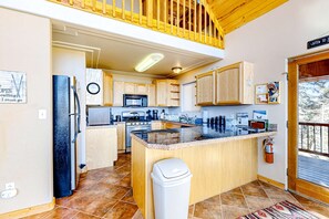 A kitchen with wooden cabinets, a central island, a microwave, and a stove. - Peter's Place - Panoramic Mountain Views & Decks (Angel Fire)
