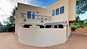 Un bâtiment moderne à deux étages, doté d’un balcon, d’un patio couvert et d’une allée gravillonnée.