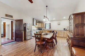 Eine geräumige Küche mit Holzboden, einem Esstisch mit Stühlen und einem großen Holzschrank.