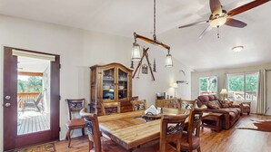 A dining area with a wooden table and chairs, a ceiling fan, and a view to the outside. - Valley Views Cottage - Close to Ski Slopes & Town (Angel Fire)