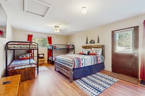 A room with bunk beds, a wooden table, a door, and a window with blinds. - Valley Views Cottage - Close to Ski Slopes & Town (Angel Fire)