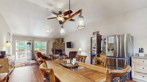 A spacious kitchen with a wooden dining table, chairs, a built-in refrigerator, and a ceiling fan. - Valley Views Cottage - Close to Ski Slopes & Town (Angel Fire)