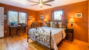 A bedroom with a bed, desk, chair, two windows, ceiling fan, and bedside lamps. - Santa Fe Serenity - Walk to the Railyard, Dog-Friendly Garden Home (Santa Fe)