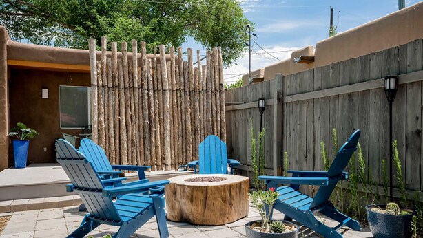 A patio area with blue Adirondack chairs, a wooden fire pit, and potted cacti. - Santa Fe Serenity - Walk to the Railyard, Dog-Friendly Garden Home (Santa Fe)