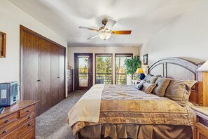 Ein Schlafzimmer mit Bett, Schminktisch, Deckenventilator und Blick ins Freie.