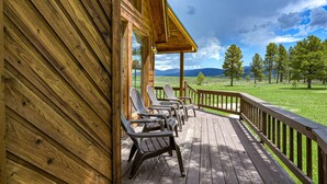 Eine Holzterrasse mit Stühlen und Blick auf eine grüne Landschaft und Berge.