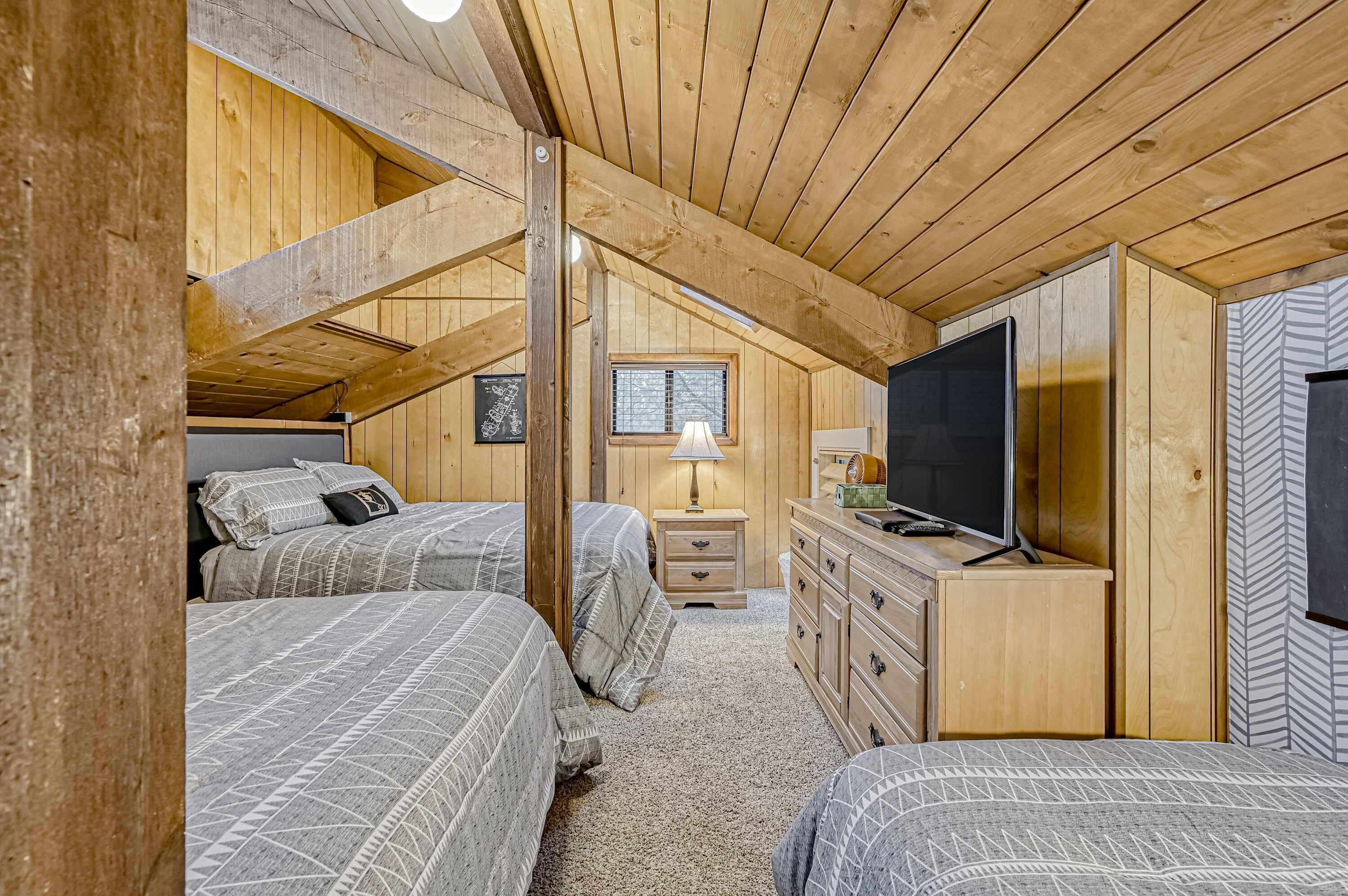 Een gezellig slaapkamer op zolder met houten balken, twee bedden, een dressoir, een televisie en een raam.