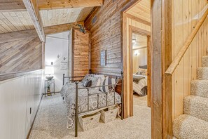A wooden cabin bedroom with a metal bed frame, a small bedside table, and a door leading to another room. - Timbers Townhouse 1 - Walk to Lifts, Hike & Bike (Angel Fire)