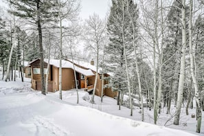Eine Hütte, umgeben von schneebedeckten Bäumen.