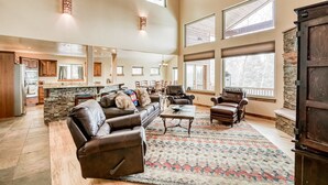 A spacious living room with leather sofas, a coffee table, and a patterned rug. - Vista Linda Cabin - Views, Sauna, Deck & Dog Okay (Angel Fire)
