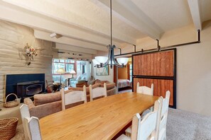 A cozy room with a wooden dining table, white chairs, a fireplace, and a rustic wooden wall.