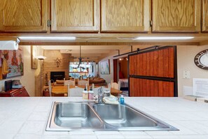 A kitchen with two stainless steel sinks, wooden cabinets, and a dining area with a table and chairs.