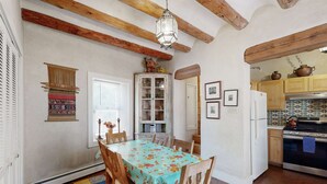 Una cucina con travi in legno, un tavolo da pranzo con sedie, un frigorifero e un fornello.