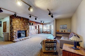 Ein geräumiges Wohnzimmer mit Kamin aus Stein, einer Couch, einem Couchtisch und einer Lampe.