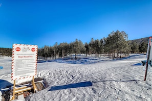 Schneebedeckte Landschaft mit einem Schild, das einen Nordic Center und einen Skilift im Hintergrund weist.