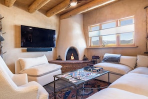 A cozy living room with a fireplace, a flat-screen TV, and a coffee table with board games.