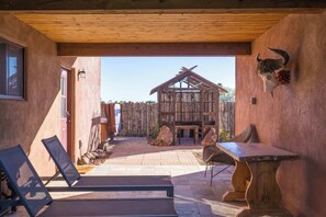 Eine hölzerne Pergola, ein rustikaler Holztisch und eine Stierkopf-Dekoration in einem überdachten Außenbereich.