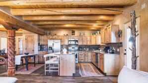 Un'ampia cucina con mobili in legno, un'isola centrale e un'area pranzo con tavolo e sedie.