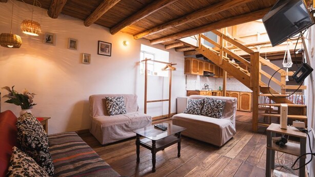 Una sala de estar acogedora con techo de madera, un sofá, una mesa de centro y un televisor.