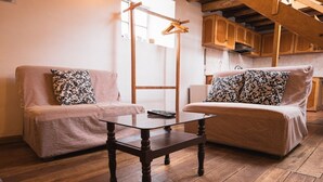 Una habitación acogedora con dos sofás, una mesa de vidrio, suelo de madera y armarios de madera.
