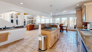 A spacious kitchen with a central island, built-in cabinets, and a dining area with a view. - Southwest Heaven - Sweeping Views, Hot Tub & Deck (Angel Fire)
