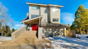 A two-story house with a red door, a covered front porch, and a garage. - Southwest Heaven - Sweeping Views, Hot Tub & Deck (Angel Fire)