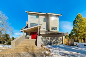 Ein zweistöckiges Haus mit roter Tür, einer Veranda und einer Garage.