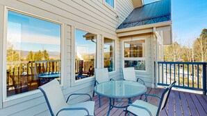 A covered patio with a glass table and chairs, large windows, and a view of trees and mountains. - Southwest Heaven - Sweeping Views, Hot Tub & Deck (Angel Fire)