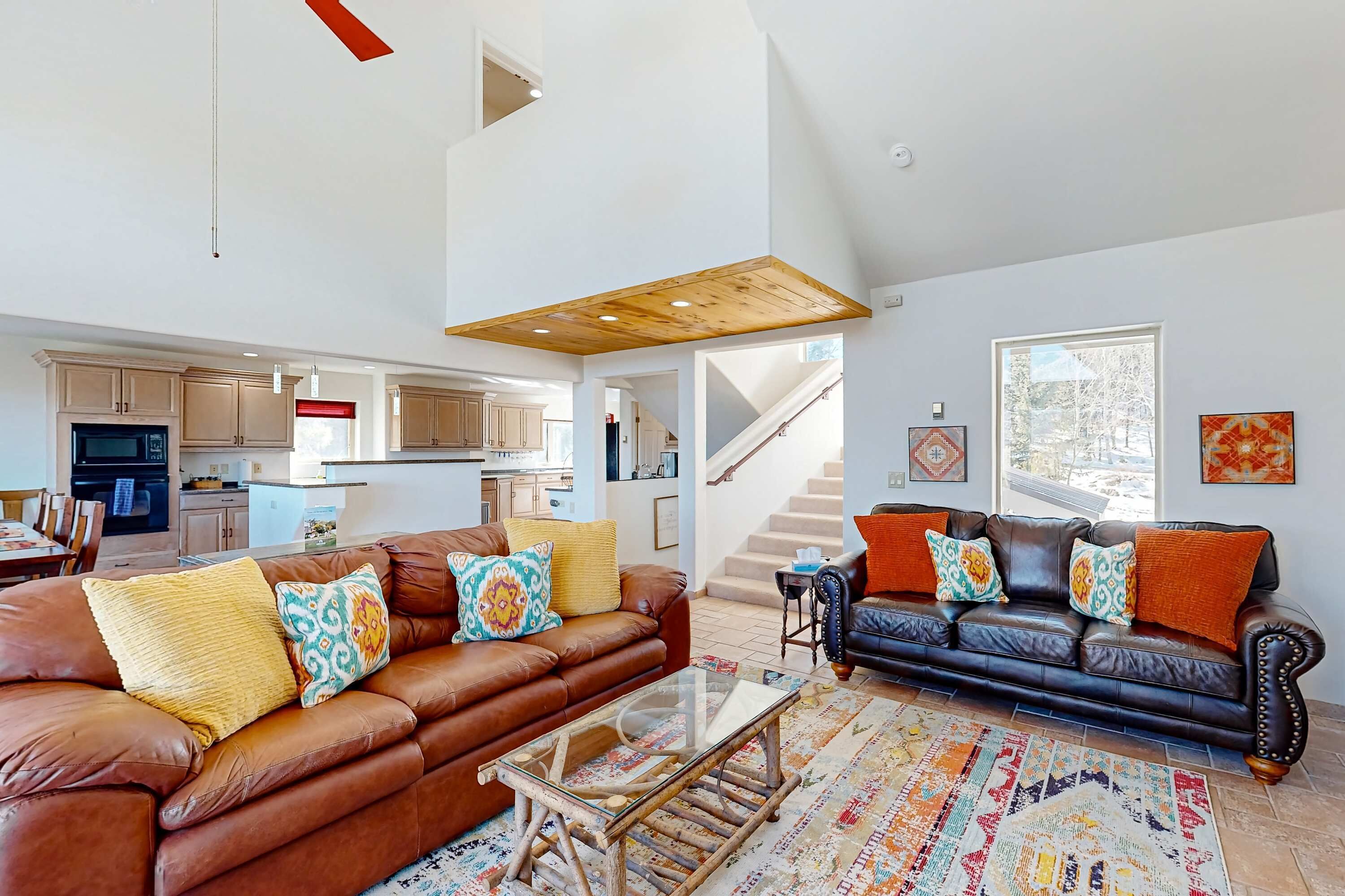 A spacious living area with two sofas, a coffee table, and a kitchen in the background.