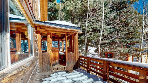 A wooden cabin with a porch, a wooden deck, and a snowy landscape. - Ridgerunner Cabin - Ski Retreat with Hot Tub (Taos Ski Valley)
