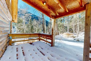 A log cabin with a wooden deck and a snow-covered ground.